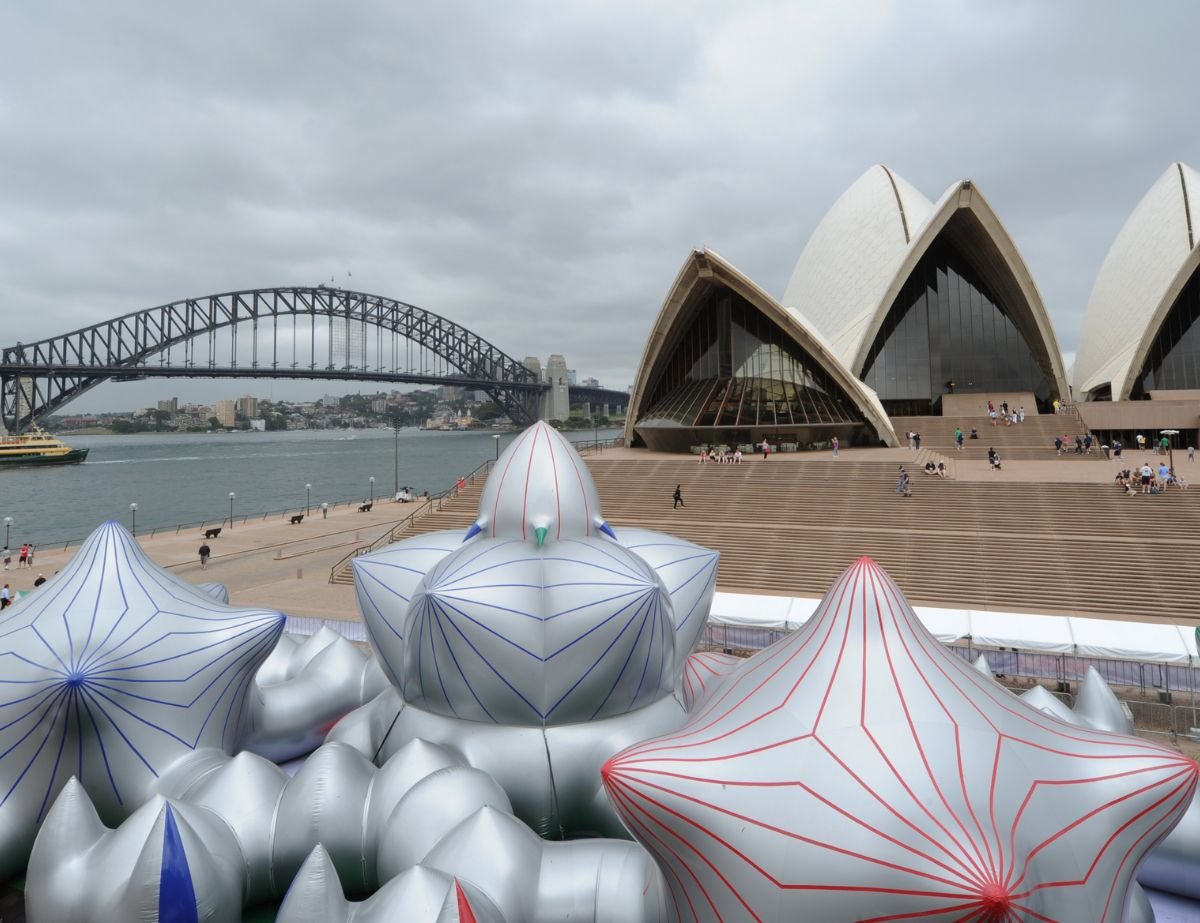 architects of air Large silver inflatable structures with red and blue lines are displayed in front of the Sydney Opera House, with the Sydney Harbour Bridge visible in the background under cloudy skies. Designed by Circular Design, a not-for-profit web design agency.