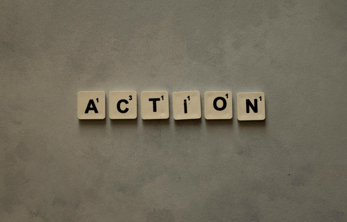 cropped-pexels-idilcelikler-31818763 Six Scrabble tiles spell out the word "ACTION" on a plain, textured gray surface—perfect for illustrating dynamic website copy or engaging web copy concepts.